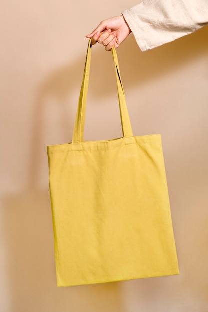 Free Photo woman holding a yellow tote bag in her hand