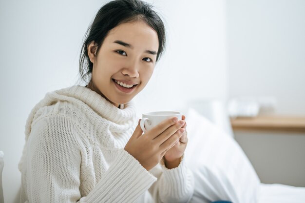 A woman holds a cup of coffee.