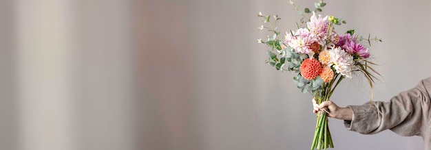 Free photo a woman holds a festive flower arrangement with bright chrysanthemum flowers