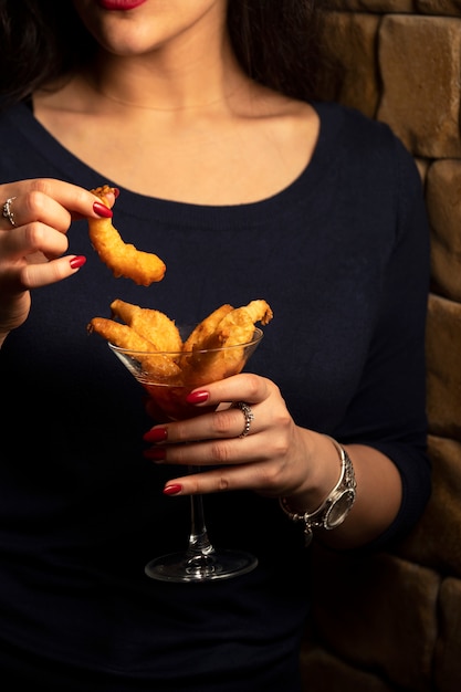 woman holds a glass of fried shrimp cocktail in sweet chili sauce