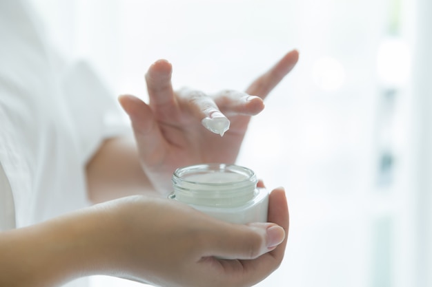 Free photo woman holds a jar with a cosmetic cream in her hands