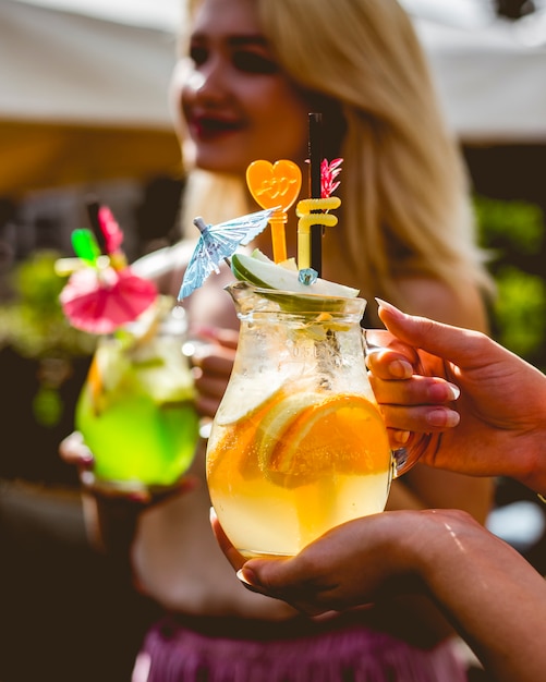 Woman holds jug citrus lemonade orange lemon apple ice side view