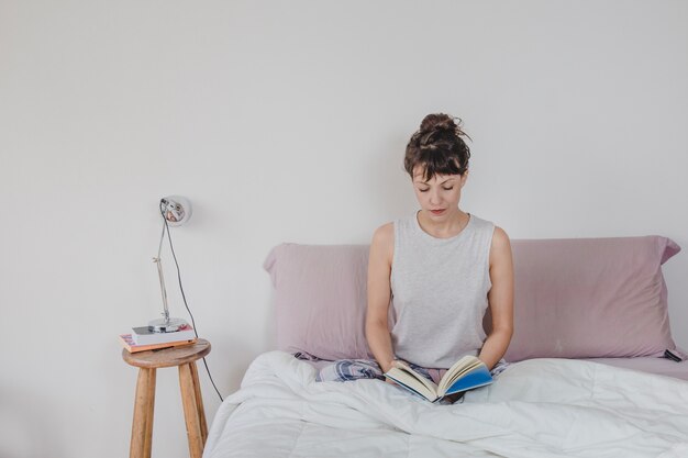 Woman at home sitting on bed reading