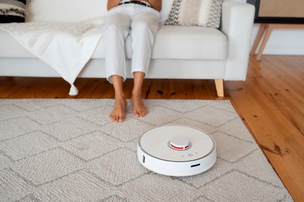 Free photo woman at home with robotic wireless vacuum cleaner