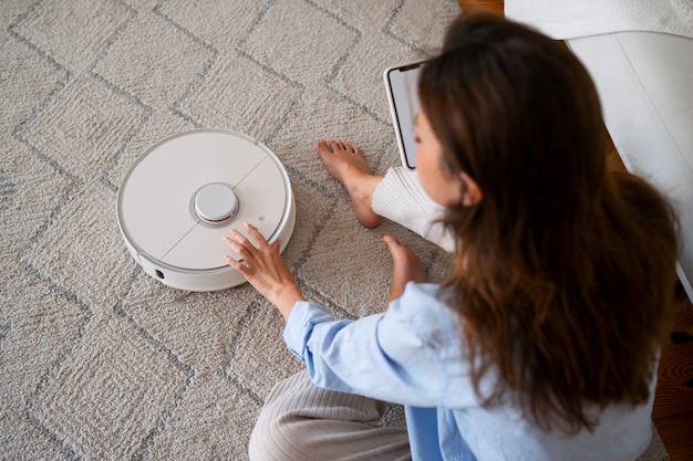 Free photo woman at home with robotic wireless vacuum cleaner