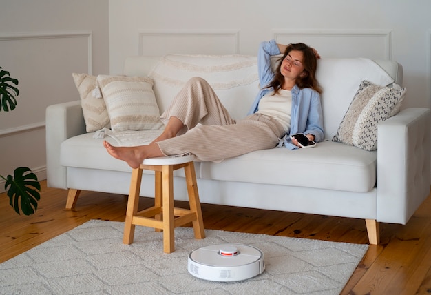 Free photo woman at home with robotic wireless vacuum cleaner