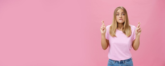 Free Photo woman hopefully looking at chart praying with crossed fingers to pass exam biting lip popping eyes standing intense and worried against pink background having hope to win or receive scholarship