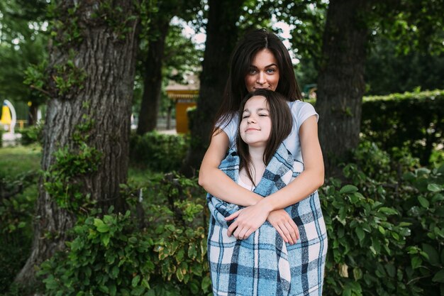 Woman hugging girl covered with blanket