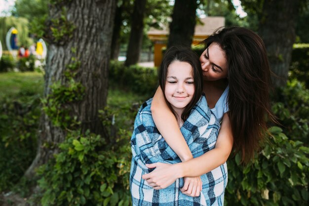 Woman hugging girl wrapped in checkered plaid