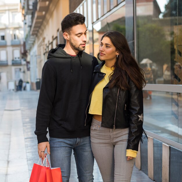 Woman hugging young man with shopping packets 