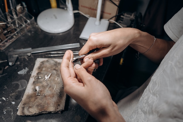 Free photo woman jeweler cuts off a piece of solder with nippers