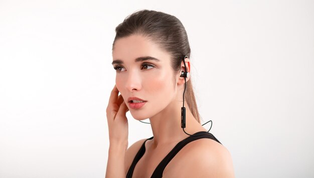 woman in jogging black top listening to music on earphones posing isolated on white