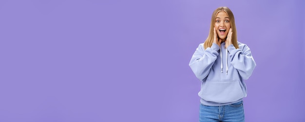 Free photo woman joyfully smiling at camera and touching cheeks as if being surprised and happy see friend