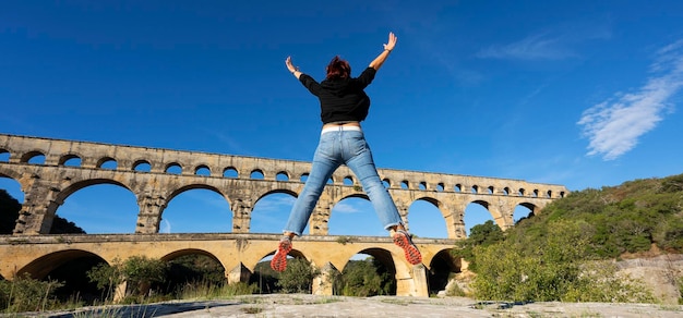 Woman jumping in front of Pont du Gard France