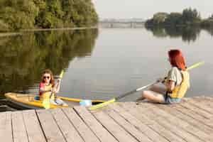 Free photo woman in kayak with friend holding paddle on dock