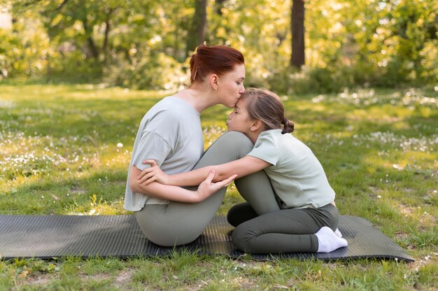 Woman and kid sitting together full shot