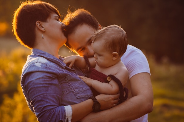 Free Photo woman kisses her man holding their little daughter 