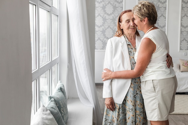 Woman kissing her senior mother at home