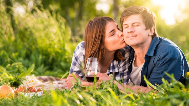 Woman kissing man on cheek in forest