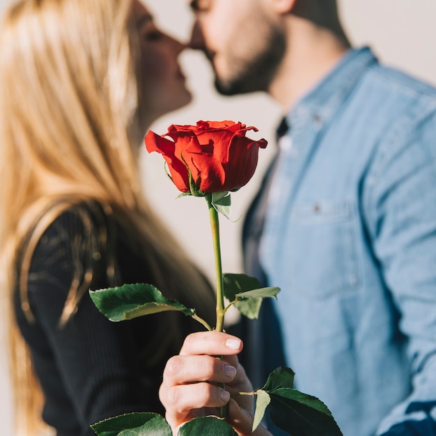 Free photo woman kissing with man and showing rose