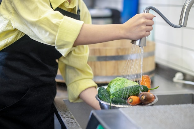 Free Photo woman in the kitchen washing vegetables before cooking