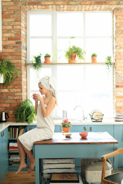 Free photo woman in the kitchen with towel on her head after shower