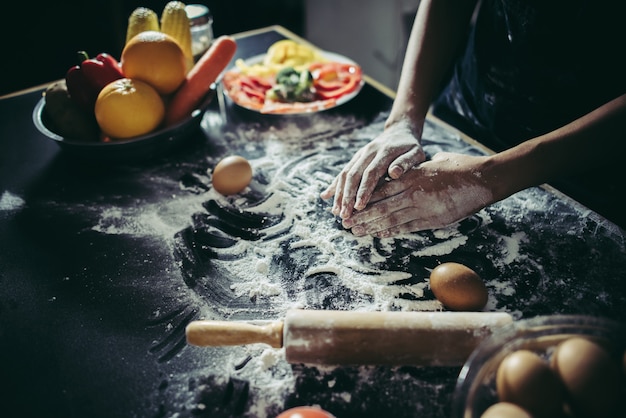 Woman kneads dough for make pizza on wooden. Cooking concept.