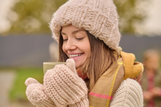 Free Photo woman in knitted clothes looking with pleasure into cup