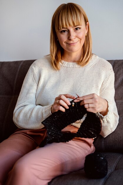 Woman knitting a black thread accessory front view