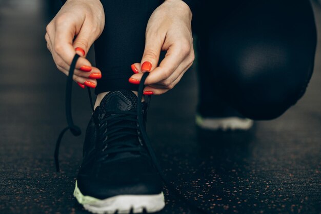 Woman lacing sneakers at the gym