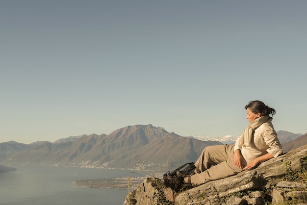 Free Photo woman laying on the rock with a beautiful view of a mountain near the seashore