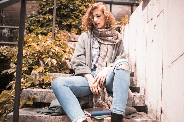 Free photo woman leaning on steps near books