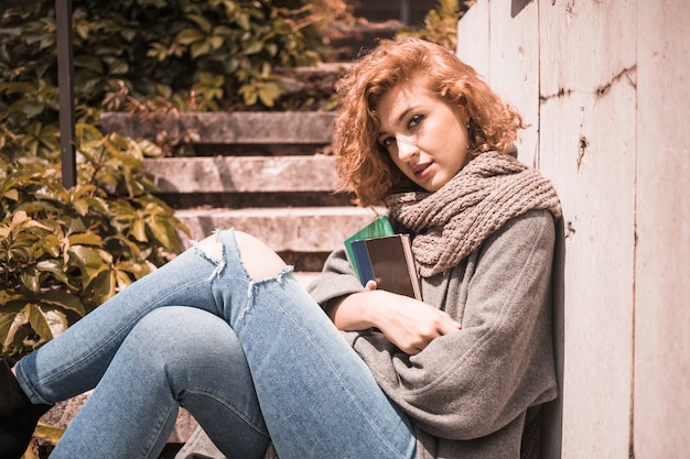 Free photo woman leaning on wall and holding books