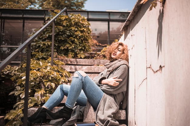 Free Photo woman leaning on wall near steps 