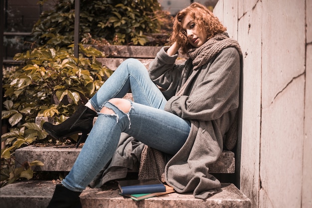 Free photo woman leaning on wall and sleeping on steps