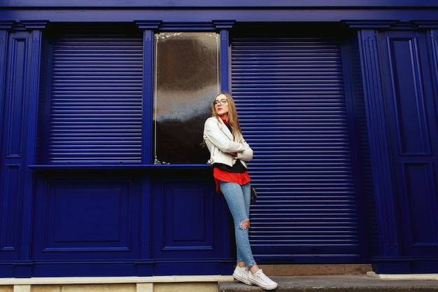 Free photo woman leans to a blue door standing on the street