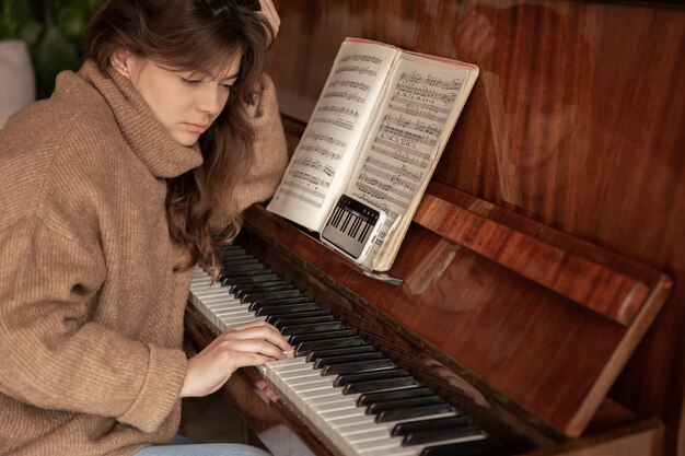 A woman learns to play the piano using an application on her phone