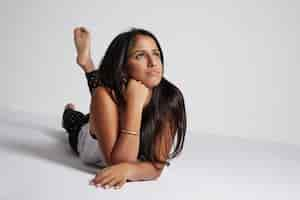 Free photo woman lies down on white floor in studio