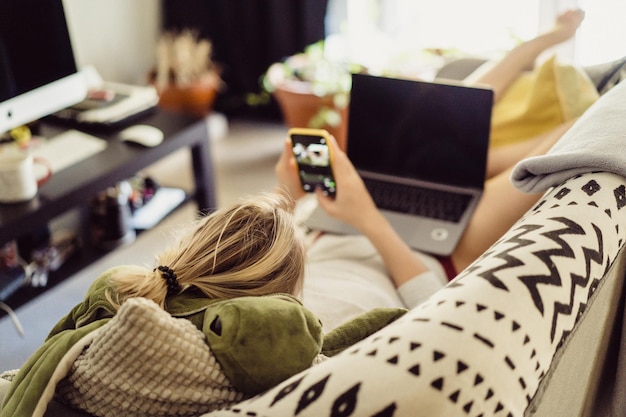 Free photo woman lies on a sofa with a laptop. leisure on isolation. working on a laptop from home.