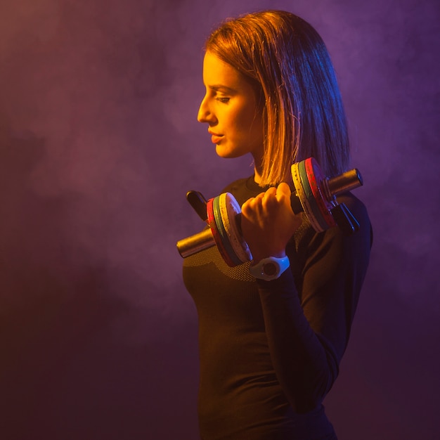 Free photo woman lifting dumbbell in smoke