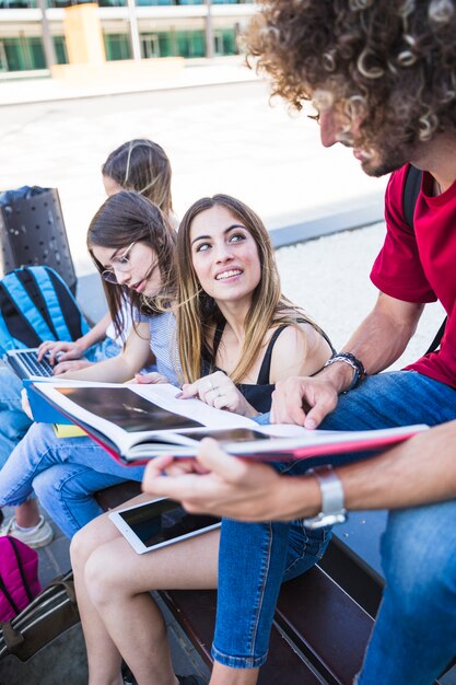 Woman listening to man while studying with friends