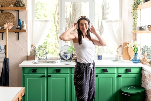 Free Photo woman listening to music in a green kitchen