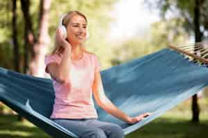 Free photo woman listening to music in hammock long view