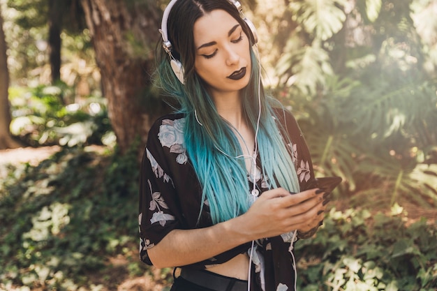 Free photo woman listening music on headphone browsing mobile phone