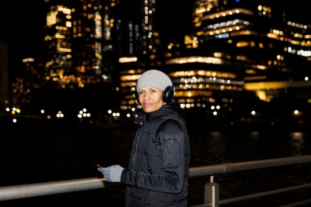 Free photo woman listening to music at night in the city