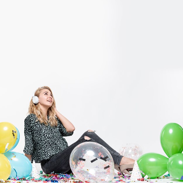 Woman listening to music surrounded by balloons