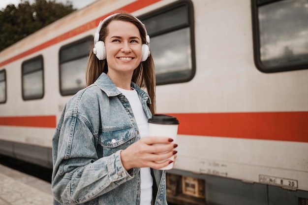 Free photo woman listening to music at the train platform