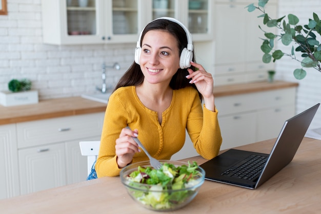 Free Photo woman listening to music while eating salad