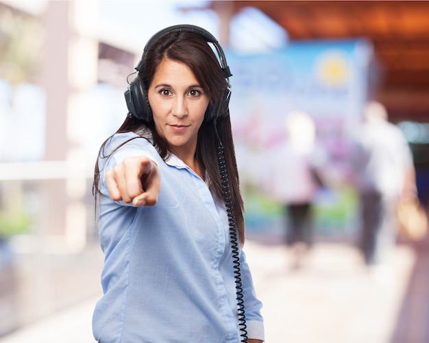 Woman listening to music with headphones and pointing to the front