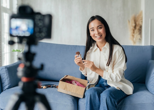 Woman live streaming at home with make up tools